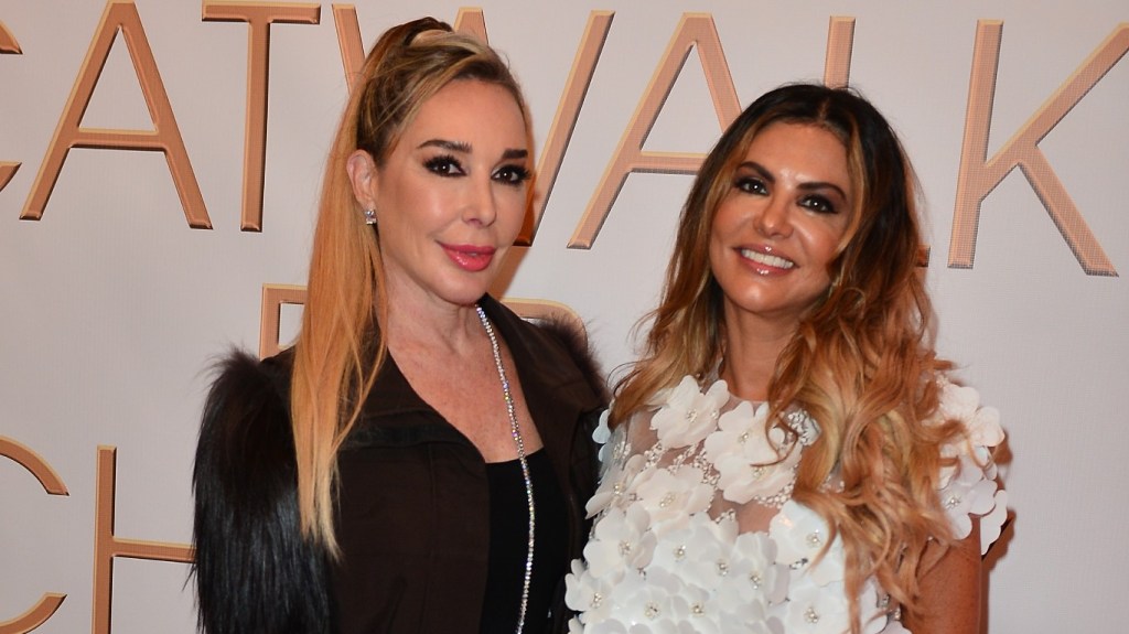 Adriana de Moura in a white top standing and smiling with Marysol Patton, who is wearing black