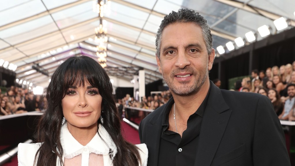 Kyle Richards with bangs in a white suit posing with Mauricio Umansky who is wearing a black suit