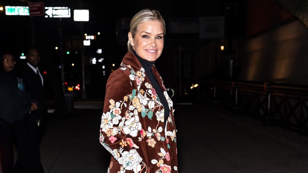 Yolanda Hadid posing in a brown coat with floral designs