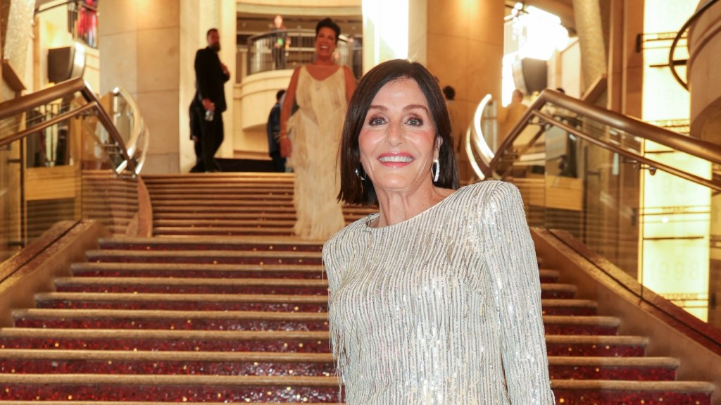 Kathy Swarts posing in a silver dress on a red staircase