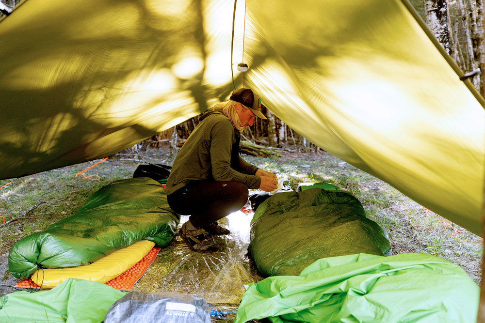 Creighton crouching in a yellow tent on Race to Survive: New Zealand