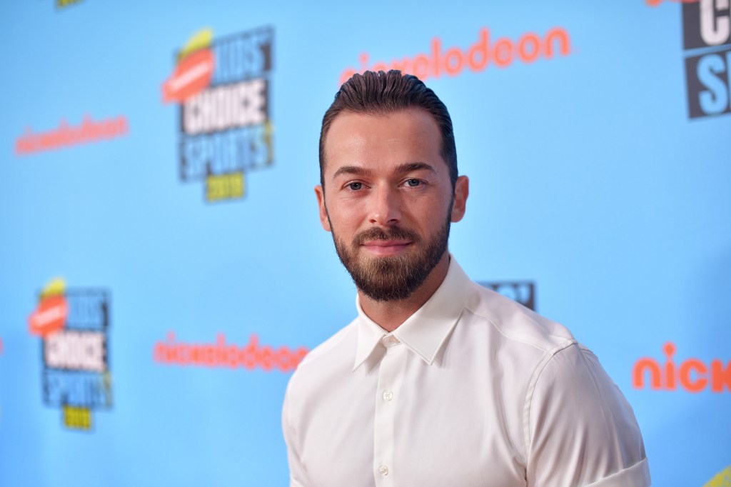 Artem Chigvintsev in a white buttuon up posing at the Kids' choice Awards