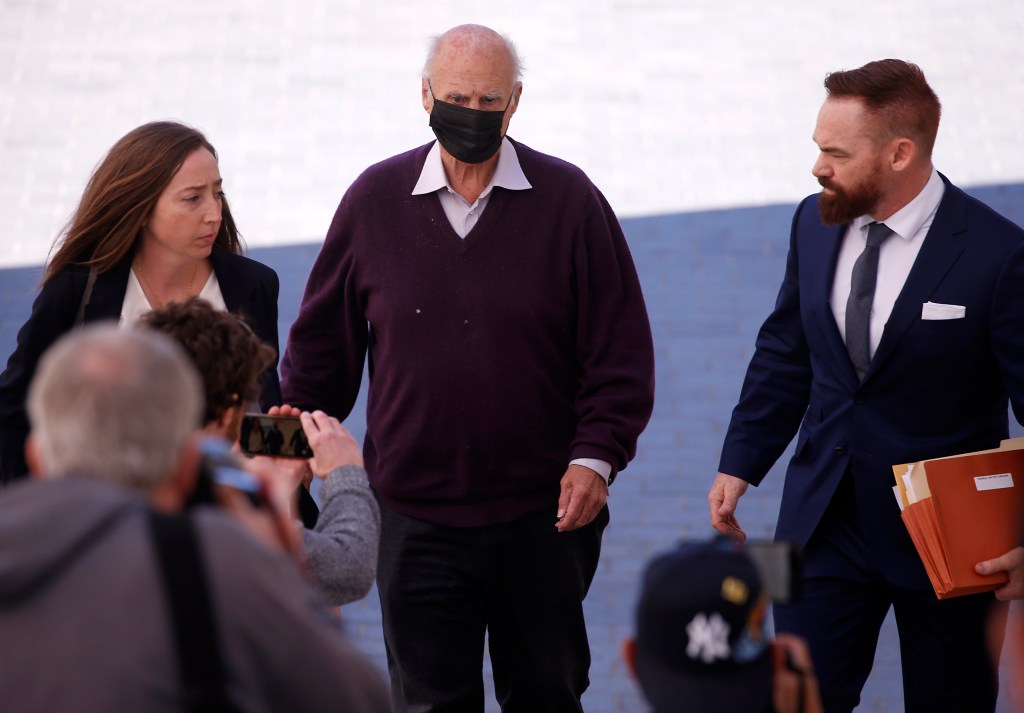 Tom Girardi wearing a mask walking among of group of people to his court hearing