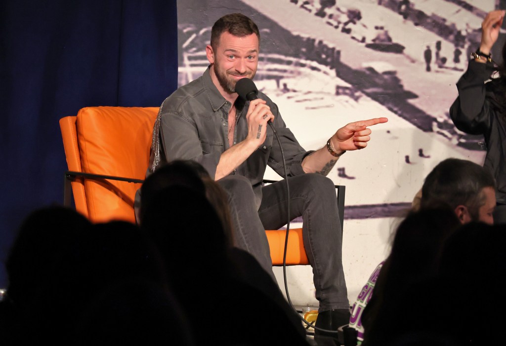 Artem Chigvintsev on a stage holding a microphone.