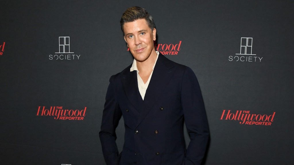 Fredrik Eklund in a black suit posing in front of a black backdrop