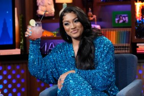 Drew Sidora wearing a sparkly blue jumpsuit and raising a glass on Watch What Happens Live