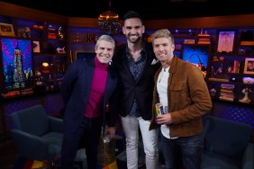 Andy Cohen in a pink turtleneck posing with Carl Radke and Kyle Cooke