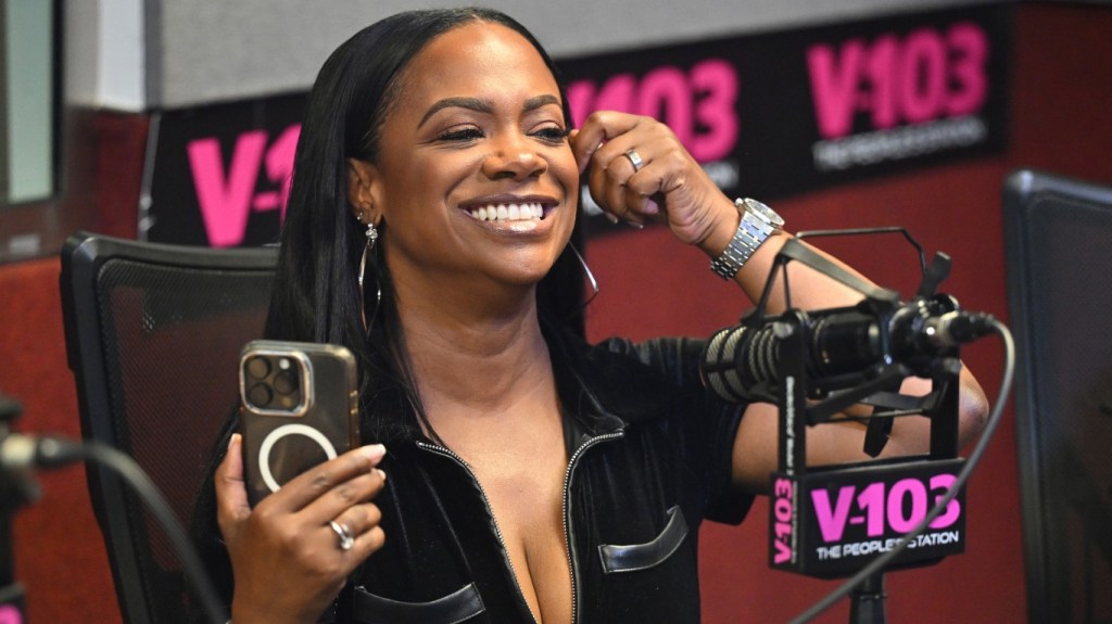 Kandi Burruss in a radio studio holding an iPhone